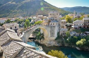 Visão do a velho ponte dentro Mostar cidade dentro Bósnia e herzegovina durante uma ensolarado dia. Neretva rio. unesco mundo herança local. pessoas caminhando sobre a ponte. foto