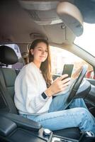 jovem mulher dirigindo uma carro e usando Smartphone inscrição para Visão uma mapa mostrando viagem rota foto