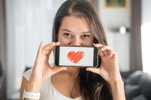 mundo saúde dia conceito. jovem mulher mostrando ilustração do coração em dela Smartphone, ilustrando a importância do cardiovascular saúde consciência em internacional saúde observação foto