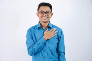 positivo ou sorridente ásia empregado homem colocando mãos em a peito ou respeito personagem vestindo azul camisa isolado em branco fundo foto