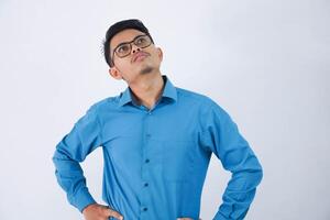 pensando ásia homem de negocios com óculos olhando acima com mãos em ancas vestindo azul camisa isolado em branco fundo foto