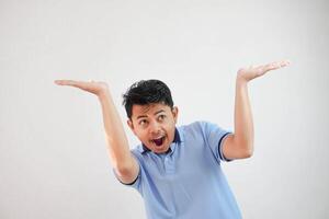 jovem ásia homem agindo gostar ele é segurando acima alguma coisa pesado, mas Está somente esvaziar cópia de espaço vestindo azul t camisa isolado em branco fundo. chocado face foto