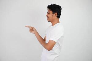 sorridente ásia homem com dedos apontando para a lado vestindo branco t camisa isolado em branco fundo foto