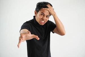 retrato do Bravo pensativo louco ásia jovem homem gritando vestindo Preto pólo t camisa isolado em branco fundo foto