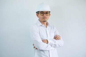 jovem ásia homem é engenheiro vestindo capacete em pé com cruzado braços e sorridente com confiante, arquiteto ou contratante, trabalhador ou trabalho, industrial conceito. foto