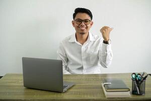 jovem ásia homem de negocios dentro uma local de trabalho apontando para a lado para presente uma produtos, vestindo branco camisa com óculos isolado foto