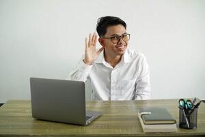 jovem ásia homem de negocios dentro uma local de trabalho ouvindo para alguma coisa de colocando mão em a orelha vestindo branco camisa isolado em branco fundo foto