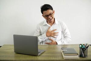 feliz jovem ásia homem de negocios dentro uma local de trabalho sorridente uma muito, vestem branco camisa com óculos isolado foto