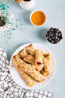 fino panquecas enrolado para dentro rolos com baga geléia em uma prato em a mesa topo e vertical Visão foto