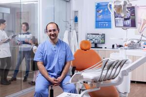 estomatologista dentro profissional dentes clínica sorridente vestindo uniforme olhando às Câmera. dentista médico discutindo com mãe e criança sobre dentes tratamento. foto