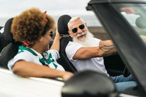 feliz Senior casal tendo Diversão dirigindo em Novo conversível carro - maduro pessoas desfrutando Tempo juntos durante estrada viagem Tour período de férias - idosos estilo de vida e viagem cultura transporte conceito foto