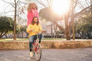 feliz casal equitação em bicicleta dentro a cidade Centro - jovem pessoas tendo Diversão ao ar livre - milenar geração e juventude estilo de vida conceito foto