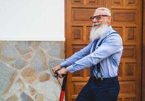 o negócio Senior homem indo para trabalhos com elétrico lambreta - feliz moda masculino tendo Diversão ao ar livre foto