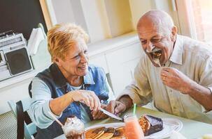 feliz idosos casal comendo panquecas dentro uma Barra restaurante - maduro pessoas tendo Diversão jantar juntos às casa - conceito do idosos estilo de vida momentos - vintage filtro - suave foco em mulher face foto