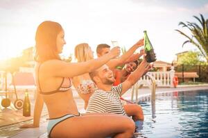 grupo do feliz amigos fazer uma piscina festa às pôr do sol - jovem pessoas rindo e tendo Diversão bebendo champanhe às churrasco festa na piscina dentro período de férias - amizade, feriados, juventude estilo de vida conceito foto