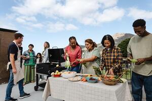 multigeracional amigos tendo Diversão fazendo churrasco às casa telhado - feliz multirracial pessoas cozinhando juntos foto