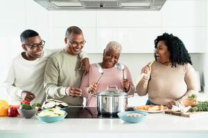 feliz Preto família tendo Diversão cozinhando juntos dentro moderno cozinha - Comida e pais unidade conceito foto