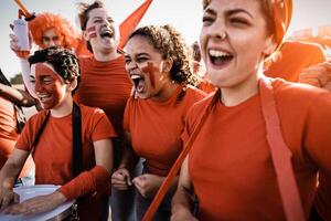 futebol fãs exultante enquanto assistindo futebol jogos às estádio - mulheres com pintado face e tambor encorajando seus equipe - esporte entretenimento conceito foto