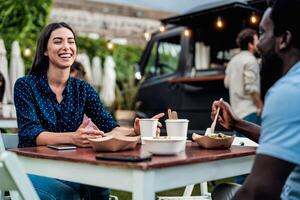 feliz multirracial amigos tendo Diversão comendo dentro uma rua Comida caminhão foto