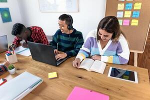 jovem multirracial alunos lendo livros e usando computador portátil dentro Sala de aula enquanto estudando juntos - escola Educação conceito - foco em fêmea foto