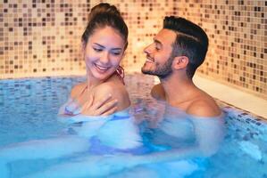 feliz jovem casal fazendo uma natação piscina spa Centro dia - romântico amantes tendo uma concurso momento em período de férias dentro recorrer bem estar hotel - relação, lazer, relaxamento e amor conceito foto