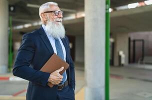 feliz Senior o negócio homem segurando digital tábua esperando dentro cidade ônibus estação foto