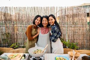 feliz sudeste ásia família tendo Diversão sorridente dentro frente do Câmera enquanto preparando tailandês Comida receita juntos às casa pátio foto