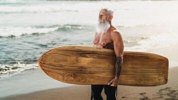 Senior em forma homem tendo Diversão surfar em tropical de praia - idosos saudável pessoas estilo de vida e extremo esporte conceito foto