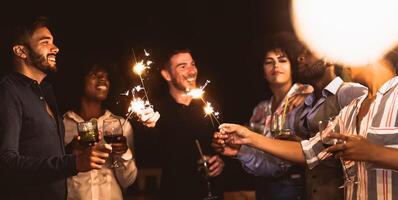 feliz jovem amigos tendo Diversão com estrelinhas fogos de artifício enquanto bebendo coquetéis em casa pátio festa - juventude pessoas estilo de vida e feriados conceito foto