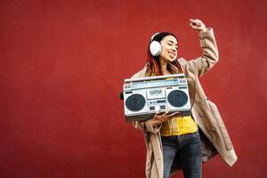 feliz jovem menina tendo Diversão dançando enquanto ouvindo música com fones de ouvido e vintage boombox estéreo foto