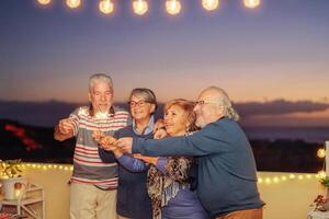 feliz Senior amigos a comemorar aniversário com estrelinhas estrelas ao ar livre - Mais velho pessoas tendo Diversão dentro terraço dentro a verão noites - conceito do amizade, aposentados e aposentadoria foto