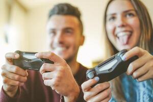 feliz amigos jogando vídeo jogos dentro seus apartamento - Hilário jovem casal tendo Diversão com Novo tendência console tecnologia - pessoas entretenimento conceito - caloroso vintage filtro - foco em masculino mão foto