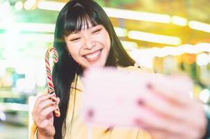 ásia menina levando selfie com Móvel telefone dentro diversão parque - feliz mulher tendo Diversão com Novo tendências Smartphone apps - juventude milenar pessoas geração e social meios de comunicação vício conceito foto