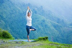 mulher dentro ioga asana vrikshasana árvore pose ao ar livre foto