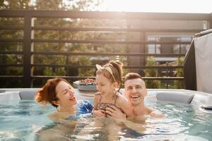 dentro verão, a família descansos dentro a ao ar livre quente banheira foto