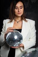 retrato do uma mulher segurando uma prata discoteca bola. ocupado dentro uma foto estúdio.