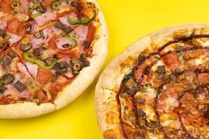 dois diferente delicioso grande pizzas em uma amarelo fundo foto