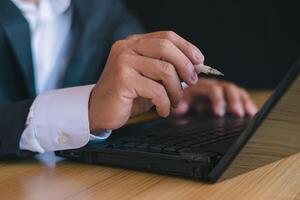 fechar acima tiro homem de negocios usando computador portátil e caderno em escritório escrivaninha foto