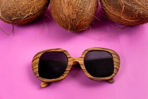 três todo cocos e de madeira óculos em uma Rosa fundo foto