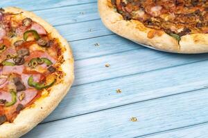 dois diferente delicioso grande pizzas em uma azul de madeira fundo foto