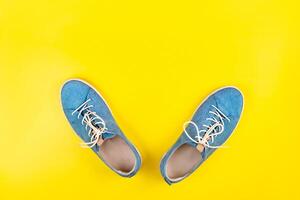 azul sapatos ficar de pé em a isolado amarelo fundo foto