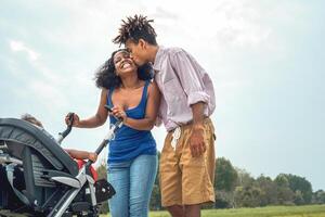 feliz africano família tendo Diversão juntos dentro público parque - afro mãe e pai com seus filha desfrutando Tempo juntos durante final de semana ao ar livre - pais amor e mãe dia conceito foto