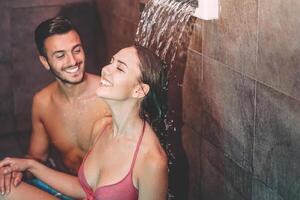 feliz casal tendo Diversão dentro luxo spa recorrer hotel - romântico jovem pessoas fazendo relaxante bem estar cascata tratamento juntos - amor relação e saudável bem ser estilo de vida conceito foto