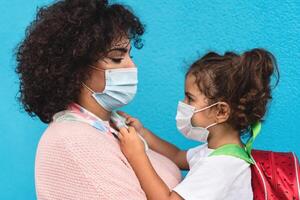 mãe e filha vestindo face protetora mascarar indo costas para escola durante corona vírus pandemia - cuidados de saúde e Educação conceito foto