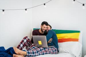 feliz gay casal tendo Diversão deitado com computador portátil dentro cama - homossexual amor e gênero igualdade dentro relação conceito foto