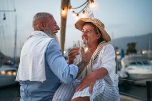 feliz Senior casal tendo Diversão brindar champanhe em barco a vela - romântico idosos pessoas a comemorar Casamento aniversário em barco viagem - amor relação e viagem estilo de vida conceito foto