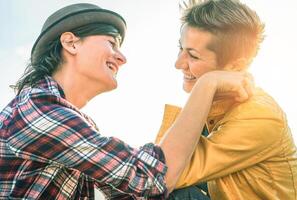 feliz gay casal olhando às cada de outros mão para mão - jovem mulheres lésbicas tendo uma concurso momento ao ar livre - lgbt, bissexualidade, relacionamento estilo de vida conceito foto