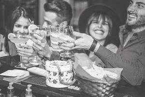 feliz amigos torcendo com calopsita dentro uma vintage Barra - jovem pessoas tendo Diversão brindar óculos do coquetéis dentro uma bar clube - amizade, feriados e juventude estilo de vida foto