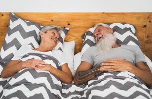 feliz Senior casal sorridente juntos dentro cama - hipster maduro pessoas tendo engraçado cama Tempo - idosos estilo de vida e amor relação conceito foto