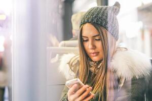 jovem mulher usando dela inteligente telefone enquanto sentado dentro uma ônibus - bonita menina conectando em dela social rede com dela Móvel telefone - conceito do juventude pessoas vício para Novo tecnologia foto